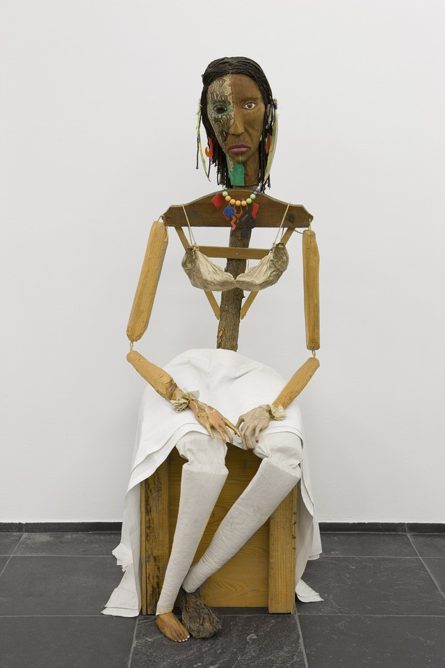 Jimmie Durham, Malinche, 1988–92. Guava, pine branches, oak, snakeskin, rope, polyester bra soaked in acrylic resin and painted gold, watercolor, cactus leaf, canvas, cotton cloth, metal, feathers, plastic jewelry, glass eye. 70 × 23 5⁄8 × 35 in. (177 × 60 × 89 cm). Stedelijk Museum voor Actuele Kunst (S.M.A.K.), Ghent, Belgium. Photo: S.M.A.K. / Dirk Pauwels.